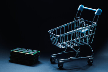 Laptop ddr memory modules stacked near toy shopping cart on black background