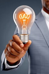 Businessman holding a lit light bulb, symbolizing ideas and innovation in a corporate setting