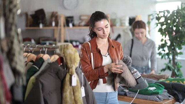  Armenian woman near showcase examine goods, buying hat. Off line clothing store from retailer. Style and fashion type look, modern trends. Designer clothing store, vintage fashion, limited edition