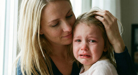 Mother comforting and hugging her crying daughter