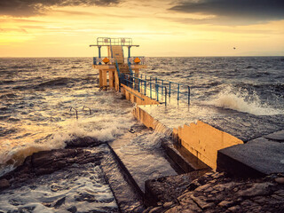 Blackrock diving tower on Salthill promenade in Galway city, Ireland. Popular city landmark. Scenic warm sun rise clouds and wild Atlantic ocean with waves. Travel and tourism.