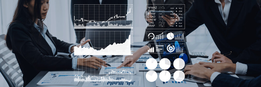 Professionals engaged in a business meeting analyze financial data using graphs and charts displayed on screens, promoting collaboration and strategic planning. Axiom - Powered by Adobe