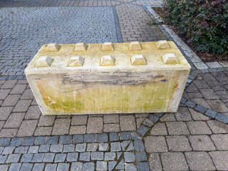 Concrete block barrier on cobblestone pavement with moss