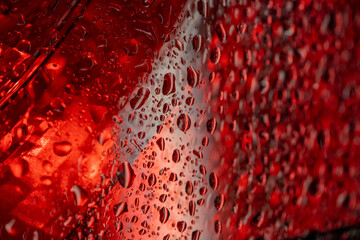 Abstract water droplets with red gradient illumination creating textured pattern with warm tonal...