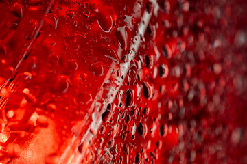 Water droplets with red illumination showing vertical flow pattern and dramatic lighting creating abstract artistic texture