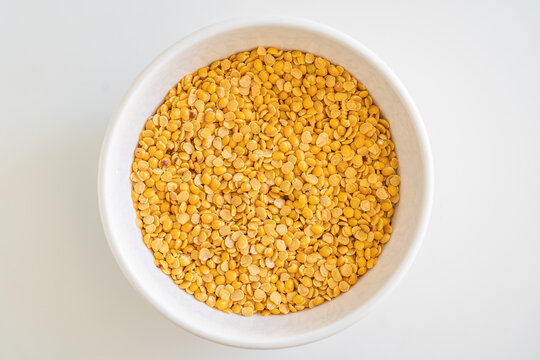 A generous heap of dried split yellow lentils (toor dal or arhar dal) on a white surface
