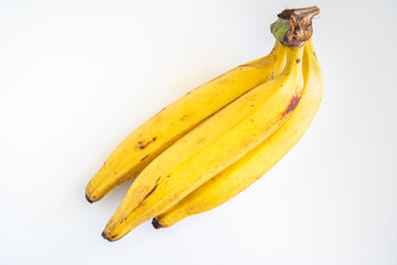 Ripe yellow plantains with a few dark spots lie together on a plain white background © Libin