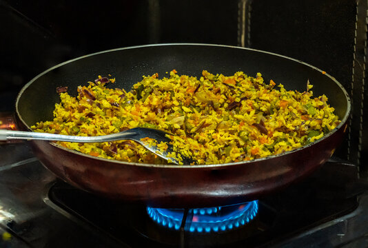 A vibrant Kerala-style thoran of cluster beans and carrots is being cooked in a pan on a gas stove