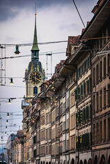 Golden clock tower above stone arcade with Christmas lights in Bern, Switzerland