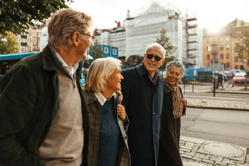 Group of senior friends walking side by side on sidewalk in city