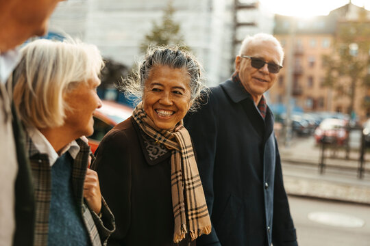 Smiling elderly woman walking with friends while spending leisure time at street