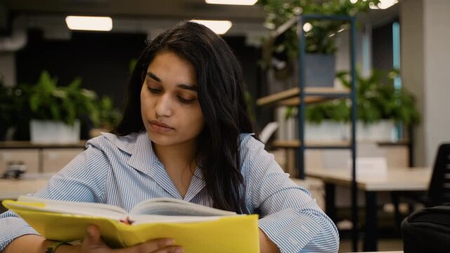 Young Indian student woman reading a book in the library
