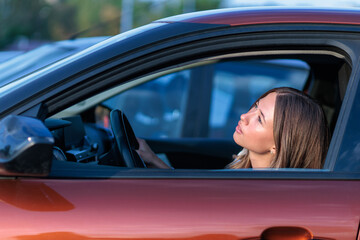 Young woman looks at the sky from her car, checking the weather