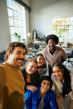 Portrait of happy businessman taking selfie with colleagues in startup office