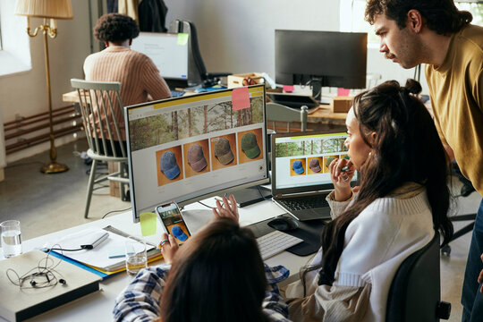 Female and male computer programmers discussing ideas for digitally generated images on computer in office