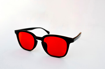 Modern black glasses with red lenses shown at an angle, designed for digital eye protection and sleep support through blue light filtering.