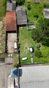 Vis&atilde;o a&eacute;rea de um homem cortando a grama de um jardim residencial, mostrando cuidado com paisagismo, manuten&ccedil;&atilde;o de &aacute;reas verdes e rotina ao ar livre.