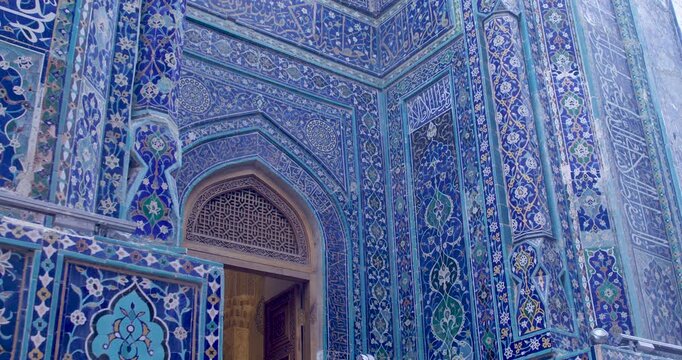 Richly decorated facade of historic Islamic architecture in Samarkand featuring detailed ceramic tiles, geometric ornament, and traditional arched doorway.