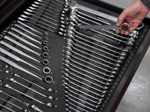 Hand selecting wrench from organized professional tool drawer showcasing automotive workshop equipment