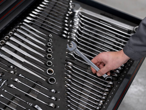 Hand placing wrench in organized toolbox drawer showing professional automotive workshop equipment - Powered by Adobe