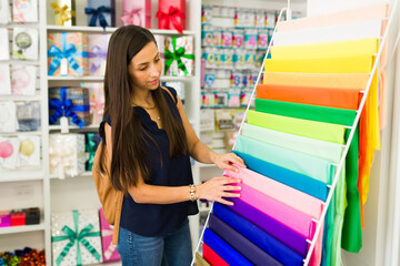 Woman choosing colorful tissue paper at gift wrap station