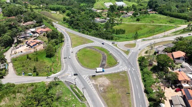 Vis&atilde;o a&eacute;rea de rotat&oacute;ria com tr&aacute;fego moderado em dire&ccedil;&atilde;o &agrave; praia, mostrando fluxo de ve&iacute;culos, mobilidade urbana e infraestrutura vi&aacute;ria em regi&atilde;o de acesso ao litoral.