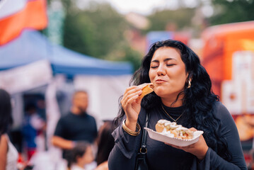 Carefree young woman indulging in hot dog while spending leisure time