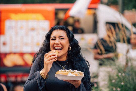 Portrait of happy young woman eating hot dog