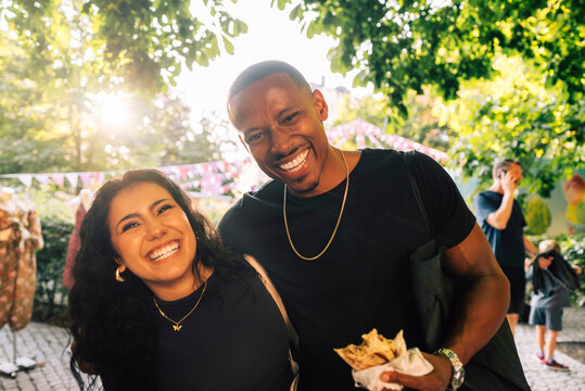 Portrait of smiling man spending leisure time with female friend in street party