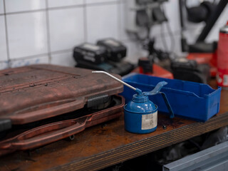 Blue oil can on workbench in automotive workshop environment with toolbox visible
