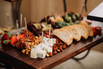 Appetizer board serving gourmet cheese, fruits, and nuts