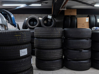 Stacked automotive tires with identification labels organized in professional workshop storage area