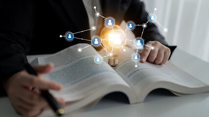 A person engages with an open book, symbolizing study and creativity; a glowing light bulb represents ideas and knowledge, merging learning with technology in a workspace. Tessel