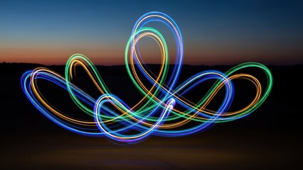 Night shot of colorful light trails against a twilight sky over dark terrain