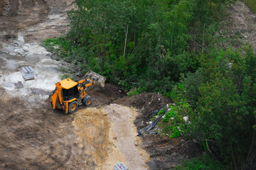 Excavator working at construction site near forest area. Heavy construction machinery preparing ground for infrastructure and urban development. Concept of construction, land development