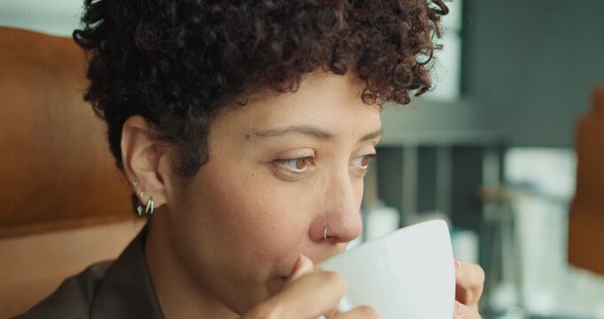 Introspective individual gazing through window while enjoying coffee