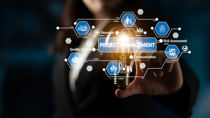 A business professional holds a glowing light bulb surrounded by project management icons. This...