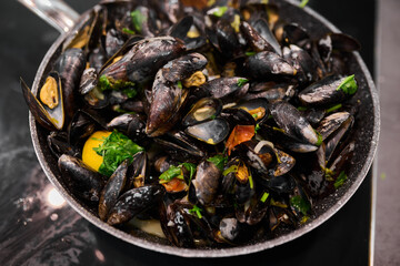 Fototapeta premium Freshly cooked mussels in a skillet with vibrant herbs and spices, showcasing a delicious seafood dish ready for serving and enjoyment