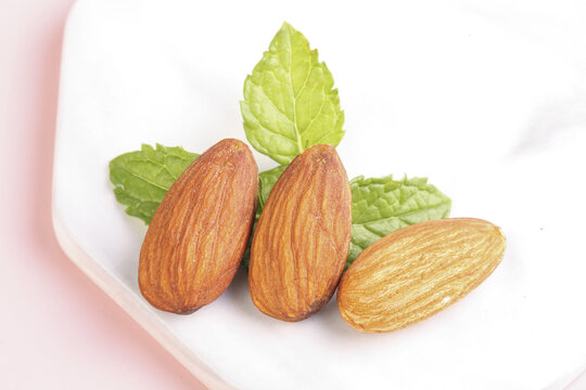 Fresh Almonds with Green Leaves on White Plate