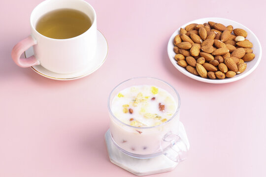Healthy Breakfast with Tea, Yogurt, Granola and Almonds on Pink Background