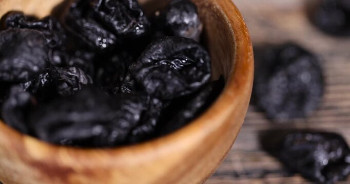 black dehydrated fruits of black plums, prunes scattered on the kitchen table, black sweet seedless prunes scattered on the table