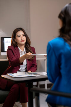 Businesswoman giving document to candidate during job interview
