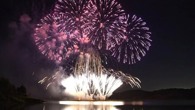 Vibrant Long Exposure of Explosive Fireworks Bursting Over Serene Lake in Night Sky
