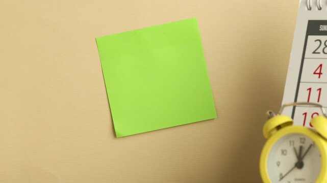 Woman sticking note on beige background, closeup