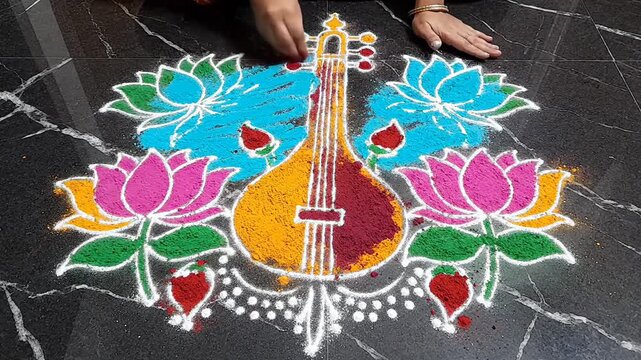 Woman Drawing Colorful Veena and Lotus Flower Rangoli for Saraswati Puja