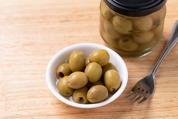 Pickled olives, Pitted green olives in a bowl and glass jar on wooden background