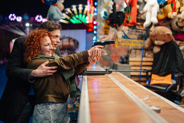 Young couple enjoying shooting gallery game at amusement park © Zamrznuti tonovi