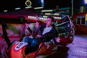 Couple screaming on fairground ride at night