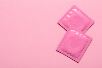 two pink condom wrappers on a pink background emphasizing the importance of protection and family planning for safe sexual health and preventing contagious diseases