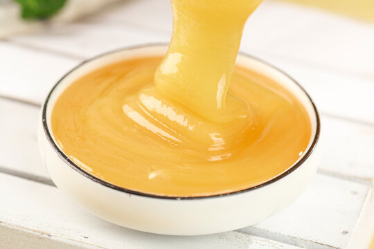Raw Honey Dripping into Bowl with Crystallized Texture